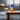 Newton's Tower rainbow acrylic blocks stacked on a sunlit table beside a modern chair