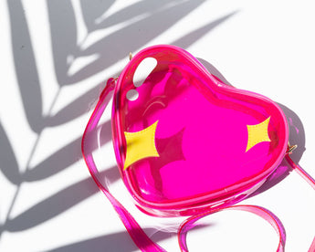 Overhead front view of hot-pink transparent heart jelly handbag with yellow sparkle accents