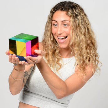 Woman holding the 95 mm Mega CMY Cube and looking at its bright overlapping colors