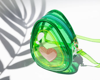 Three-quarter studio view of transparent green avocado jelly crossbody bag with heart-shaped pit detail