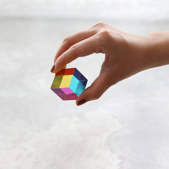 Hand holding the compact 30 mm Mini CMY Cube against a bright background